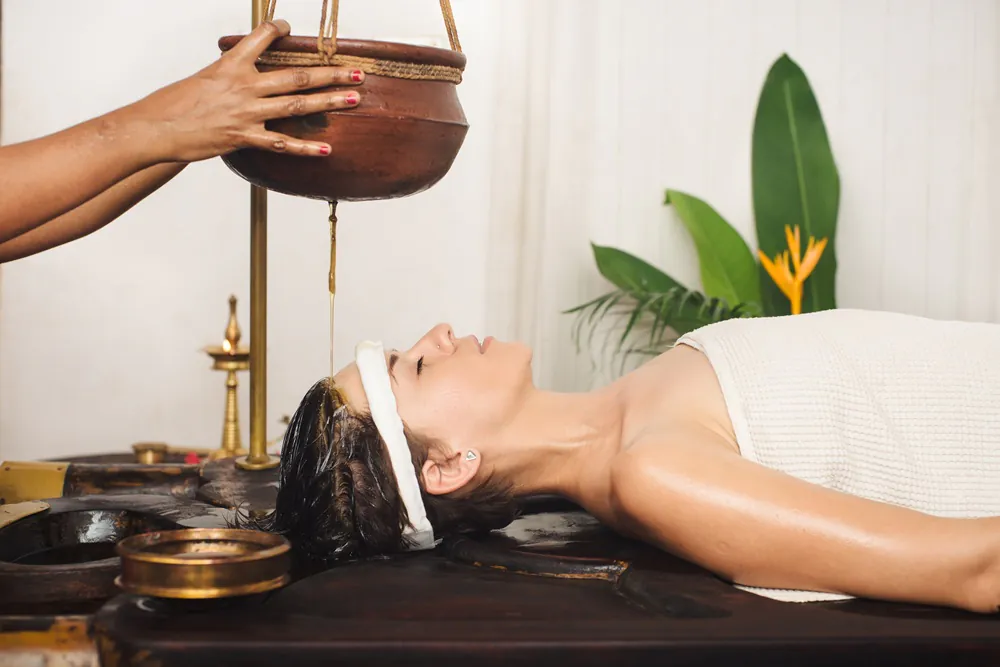 Woman receiving an Ayurvedic Shirodhara treatment