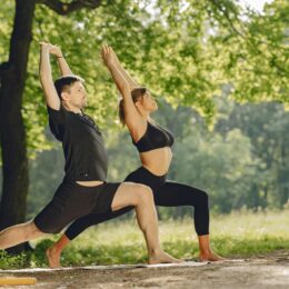 Couple practicing yoga outdoors in a serene park surrounded by nature.