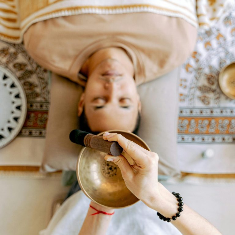 A man experiencing deep relaxation during a sound therapy session with Tibetan singing bowls for holistic wellness.